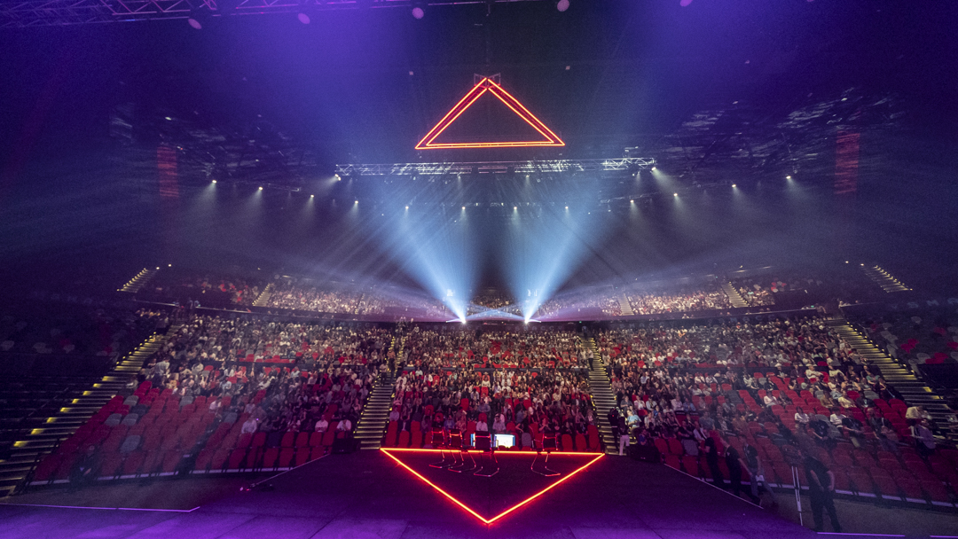 A packed arena seen from the stage during a conference session